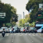 A bustling city intersection filled with cars, buses, and motorcycles during the day.