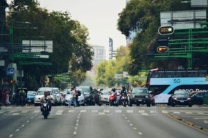 A bustling city intersection filled with cars, buses, and motorcycles during the day.